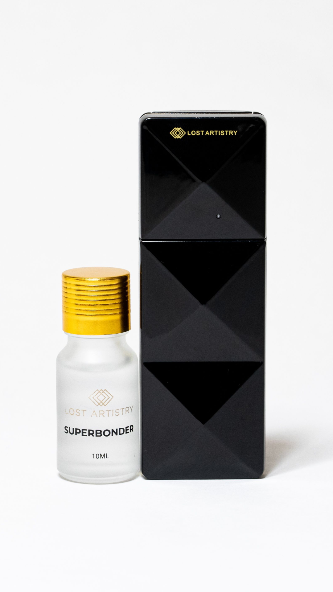 Lost Artistry Superbonder 10ml bottle with a gold cap placed beside a black geometric Lost Artistry nano mister, on a white background.