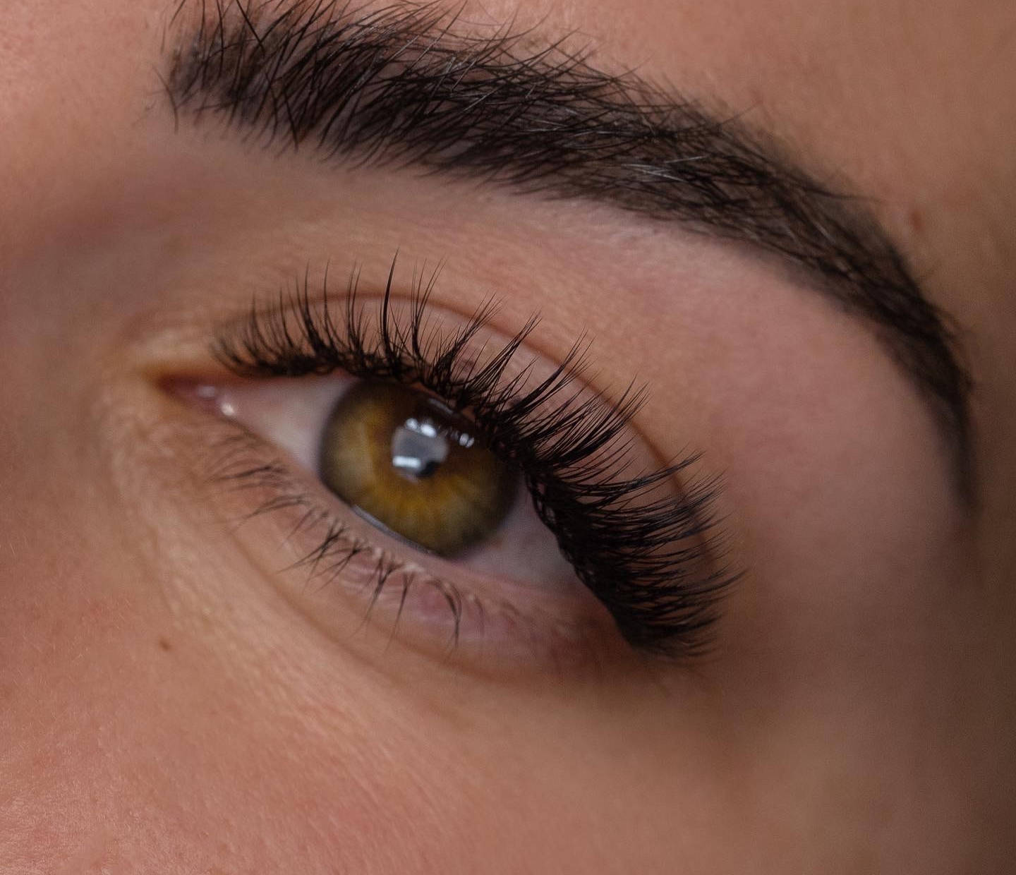 Close-up of a brown eye with long eyelashes on a neutral background