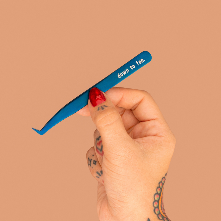 Hand holding a blue tweezer with red handle against a beige background