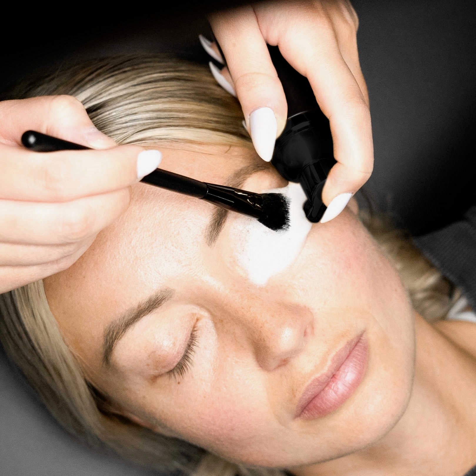 Person applying makeup with a brush to their face