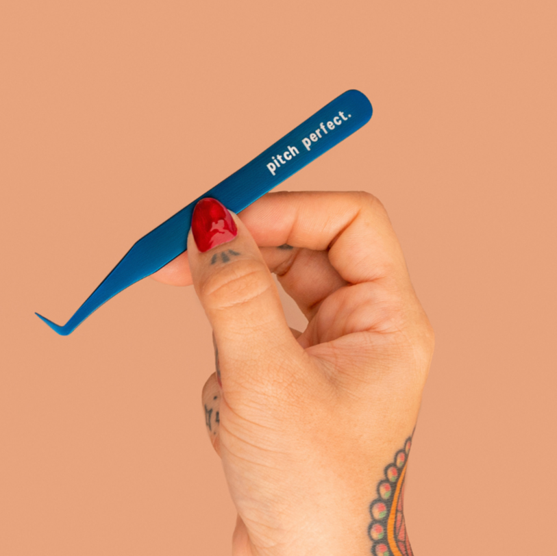Hand holding a blue tool labeled 'pitch perfect' against a beige background