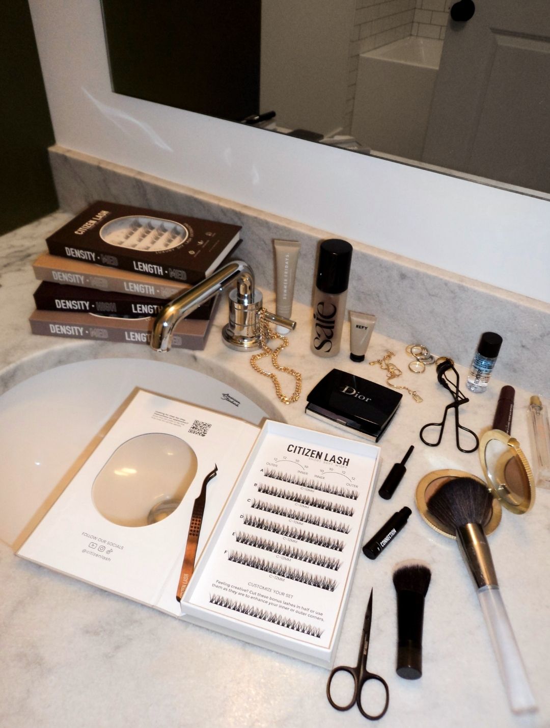 Makeup items and books on a bathroom counter with a mirror in the background