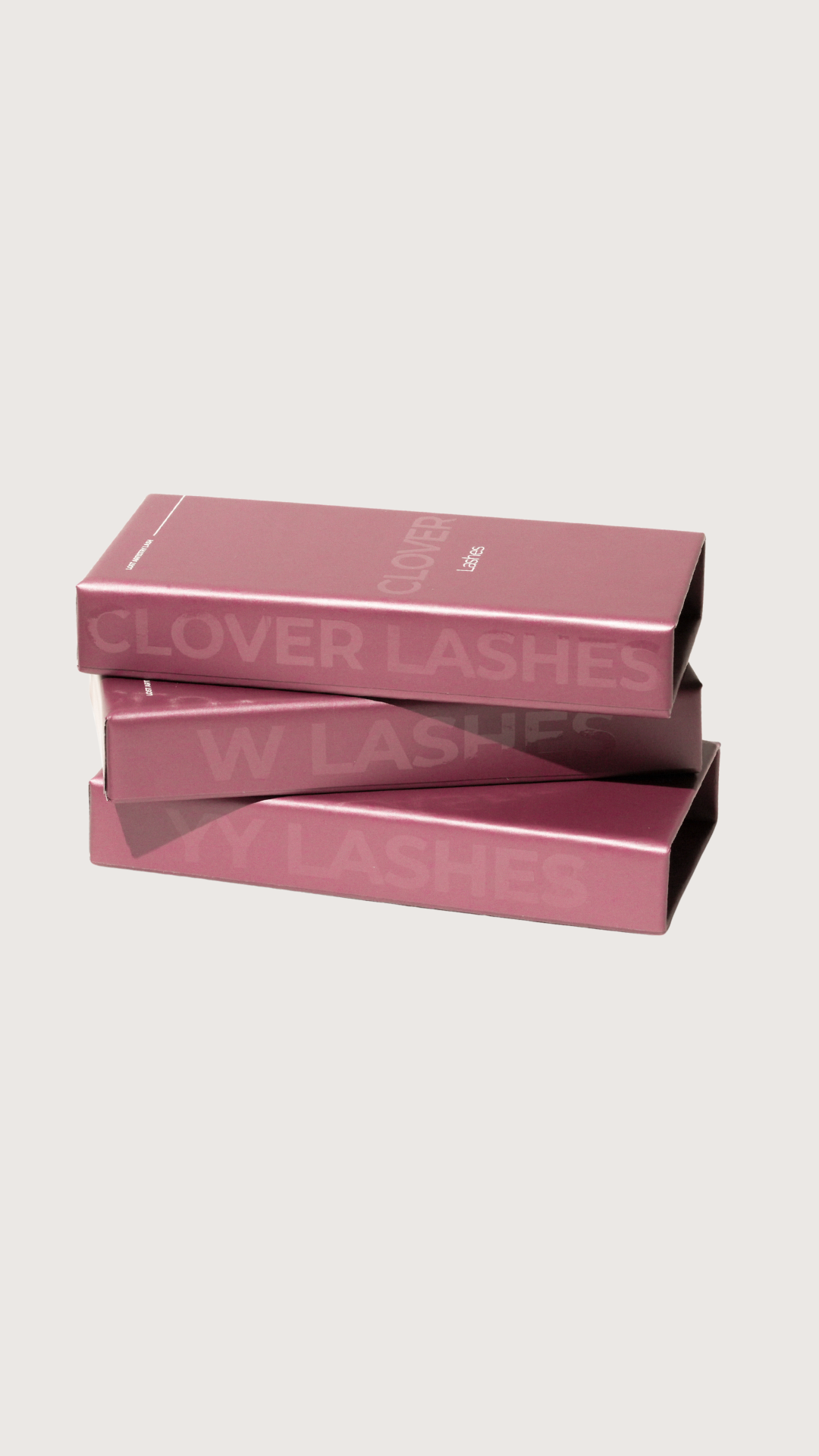 Stack of three pink lash boxes labeled “Clover Lashes,” “W Lashes,” and “YY Lashes” on a light beige background.
