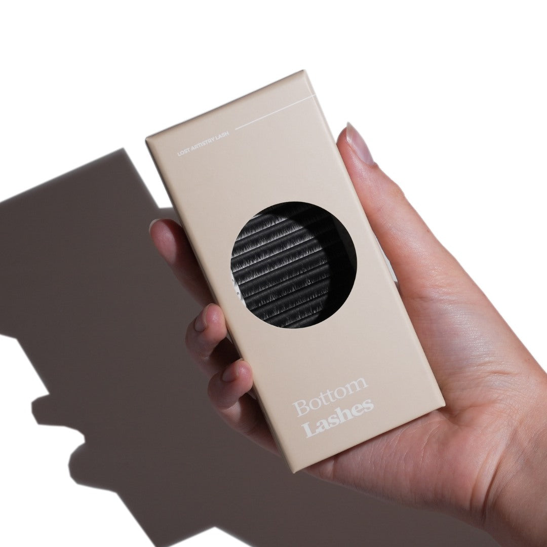 Hand holding a beige box labeled 'Bottom Lashes' against a white background