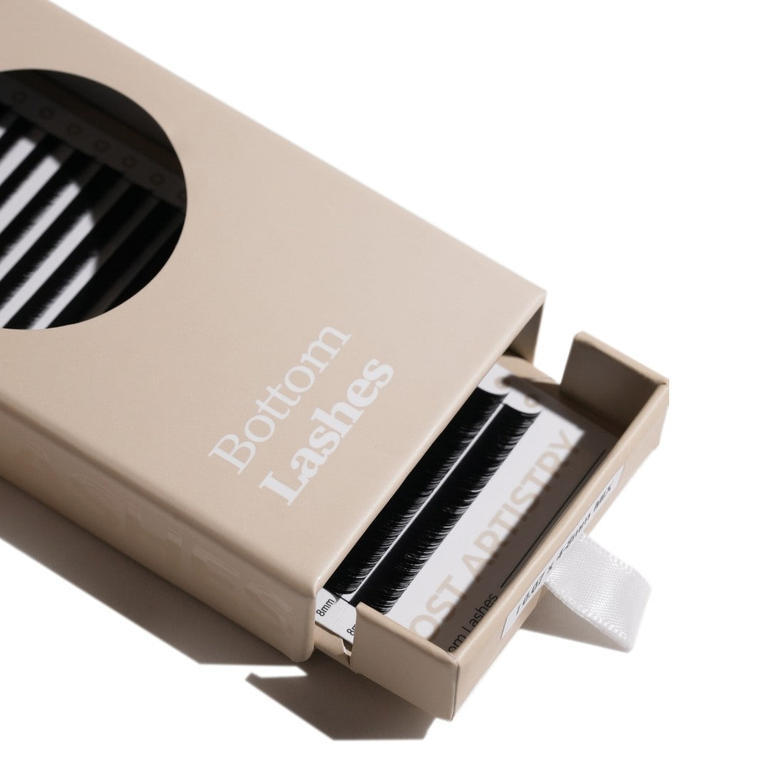 Open box containing false eyelashes with 'Bottom Lashes' text on a white background
